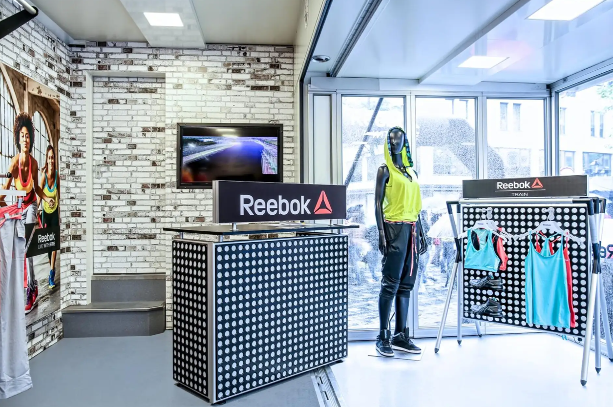An interior view of a Reebok FUTURIA mobile exhibition trailer with stylish athletic wear on display