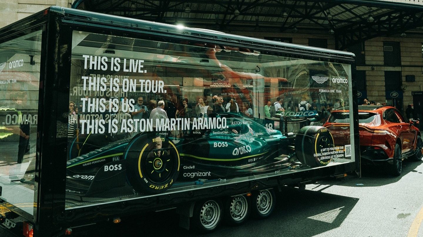Aston Martin Aramco F1 car inside The Clear Idea Transparent Showcase Box exhibition vehicle, towed by an Aston Martin DBX 707 during the 2024 UK tour
