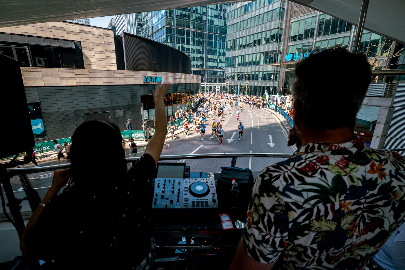 DJ view from upper deck of LED ShowTruck exhibition truck overlooking London Marathon course with Canary Wharf cityscape and runners below