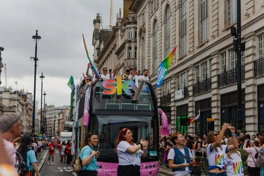 LED HyperBus promotional bus front view during London Pride parade with Sky branding guests on open top deck and crowds lining the route