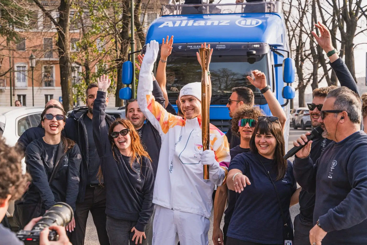 Torchbearer celebrating with the Allianz team in front of the ShowTruck during the relay
